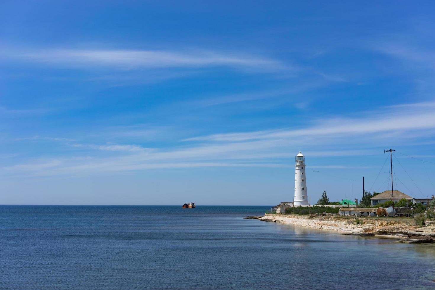 Seestück mit schönem weißem Leuchtturm auf blauem Himmelhintergrund. foto