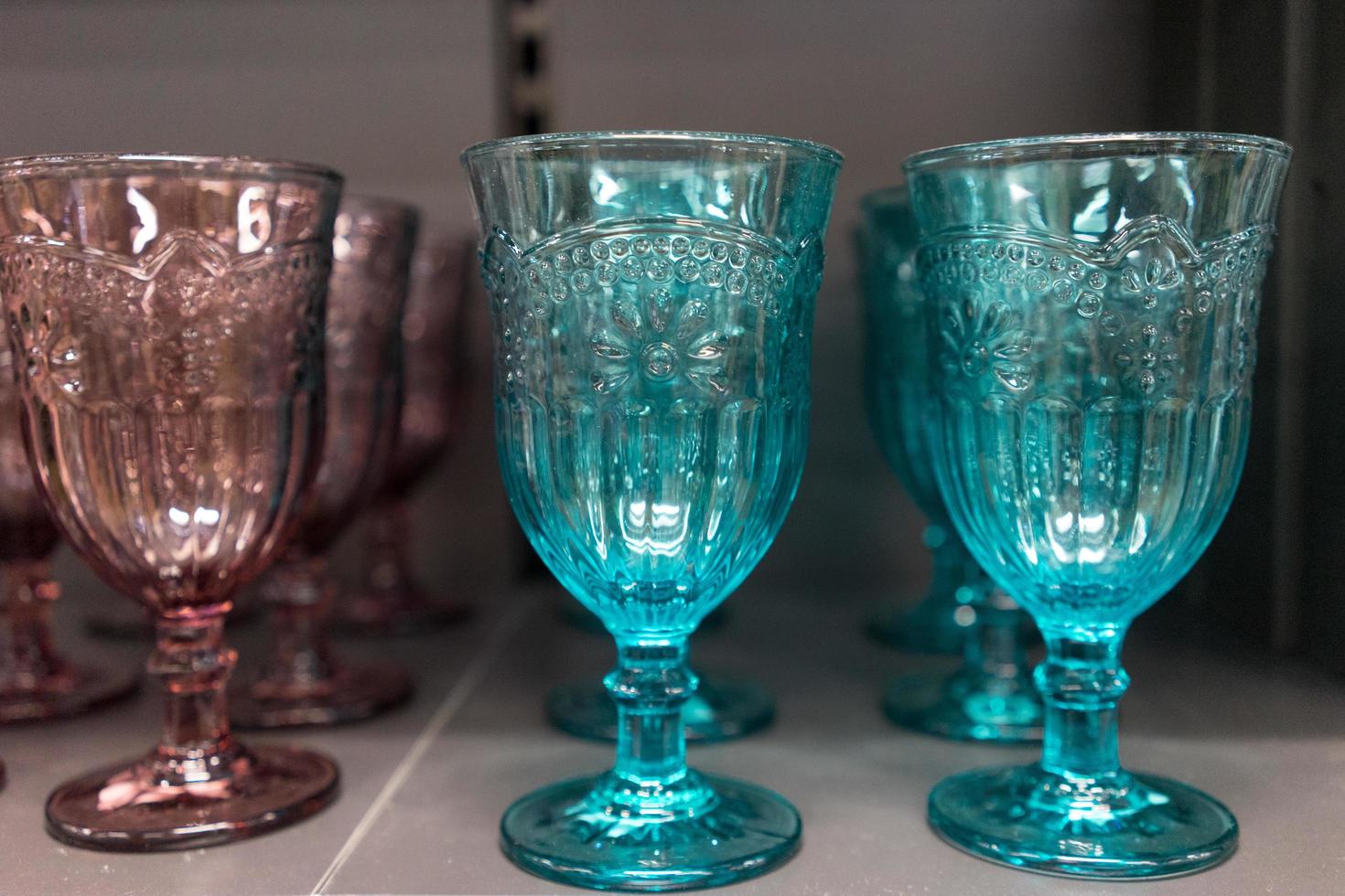 hohe geformte Gläser aus farbigem Glas, die auf einem Regal stehen. foto