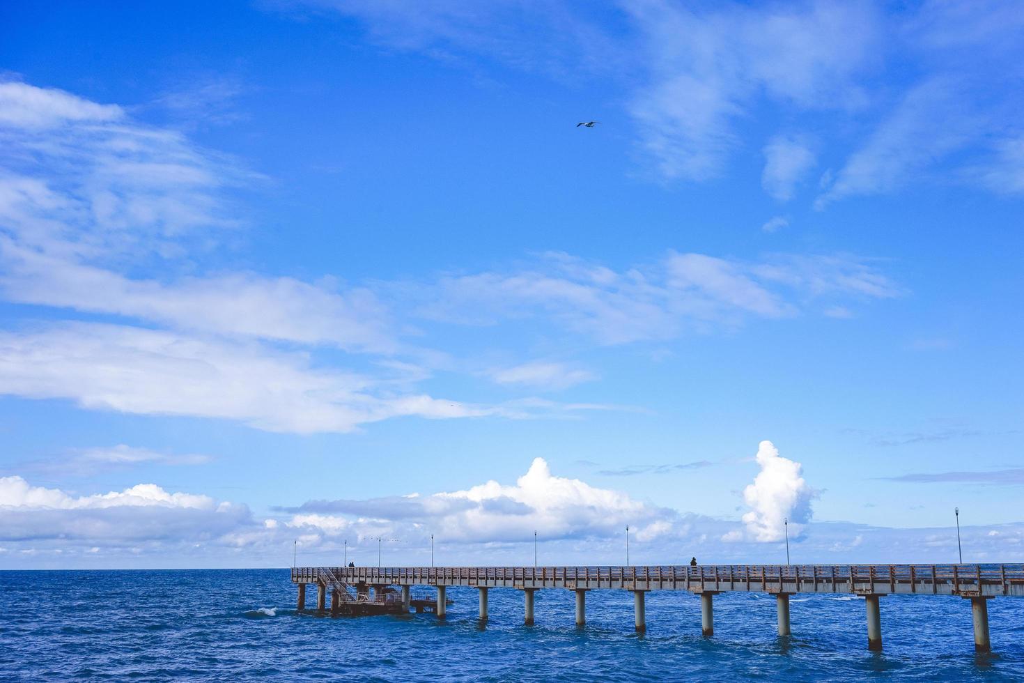 Seelandschaft mit Blick auf den langen Pier des Ferienortes mit wandelnden Menschen. foto