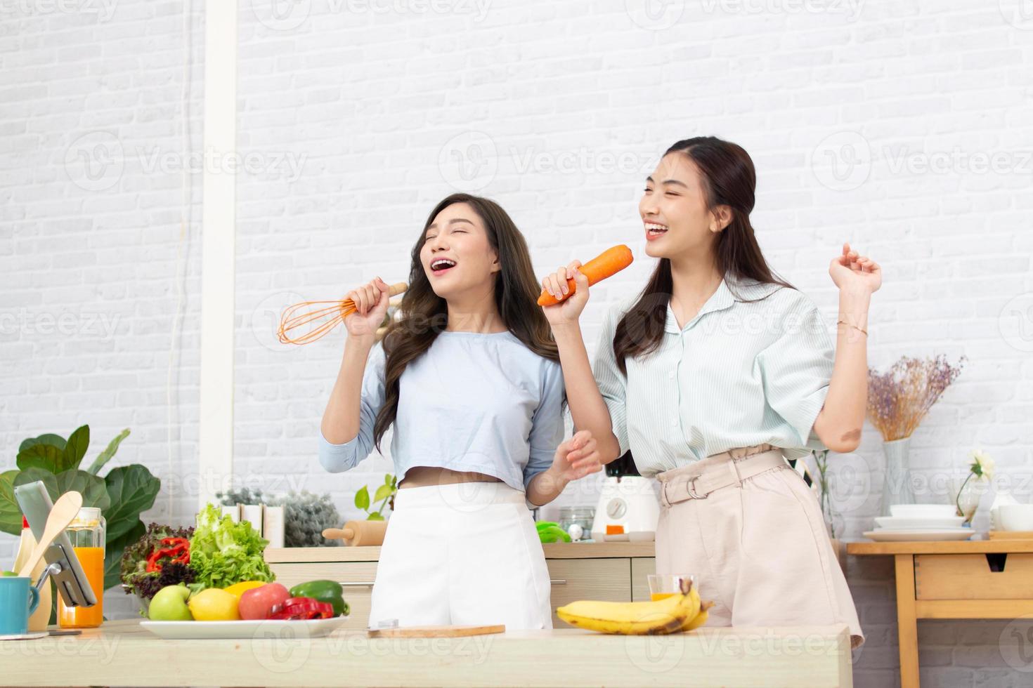 asiatische zwei frauen, die sportkleidung tragen, essen gesunde lebensmittel in der küche. junges schönes mädchen glücklich und genießt es, obst gesunde lebensmittel zu essen. foto