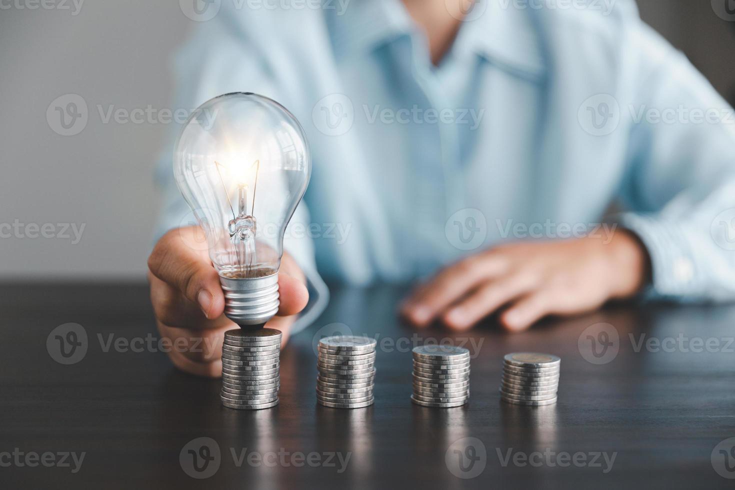 Geschäftsfrau Hand halten die Glühbirne mit Stapel Münzen. Idee von Speichern Energie und Buchhaltung Finanzen im Zuhause und Familie, speichern Welt und Energie Leistung. speichern Energie planen Konzept foto