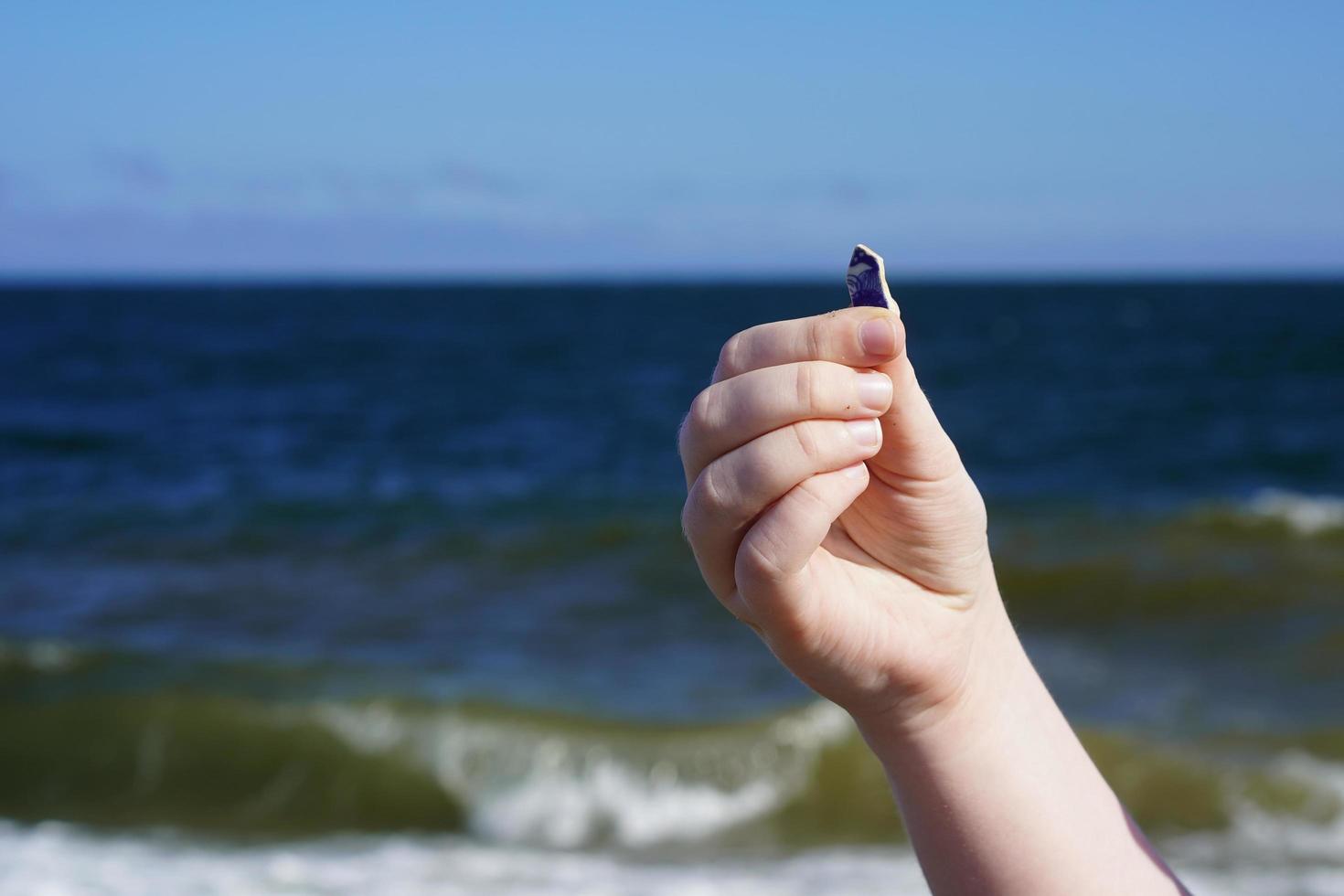 Kinderhand mit Seeglas auf dem Meereshintergrund. foto