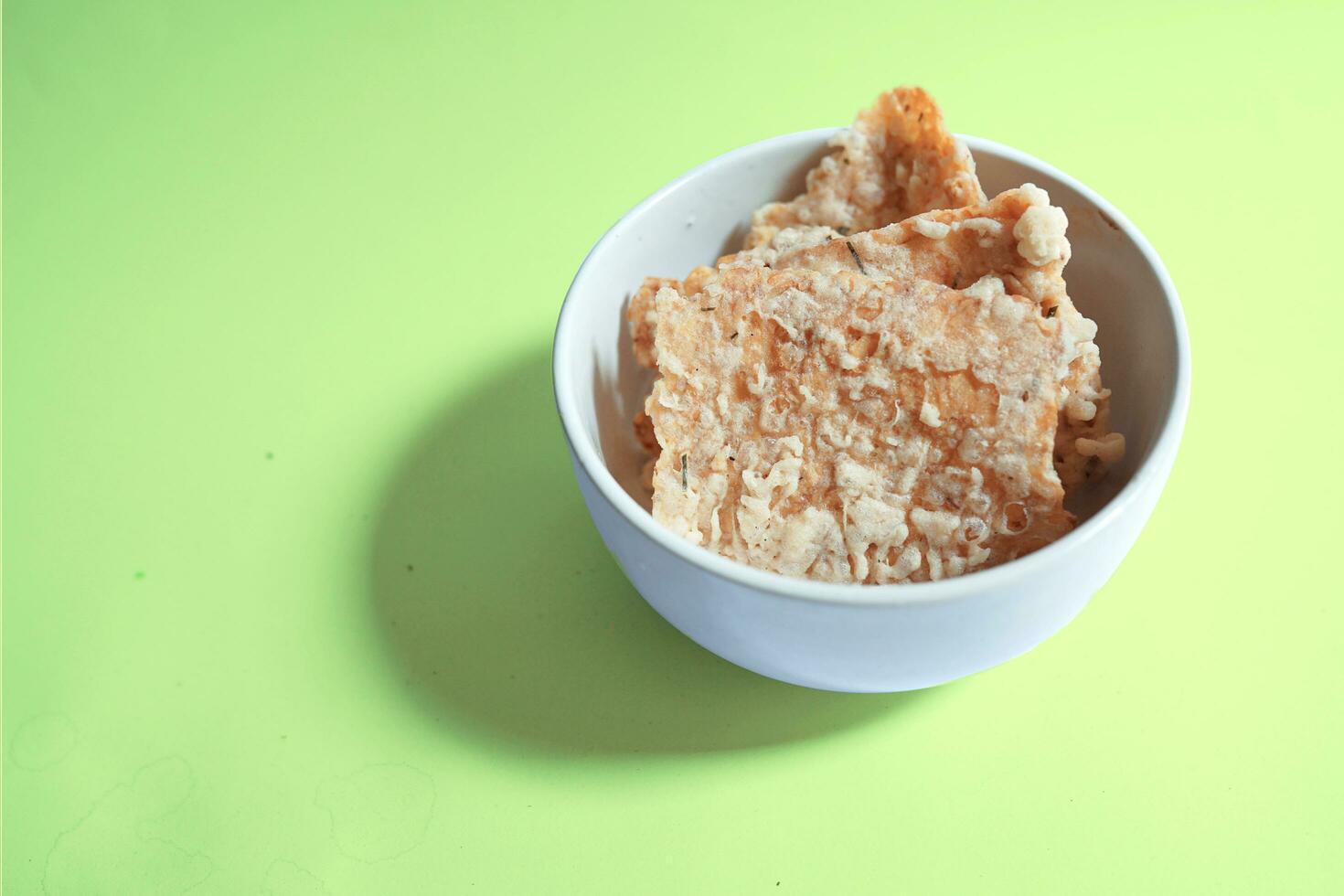 Bohnenkraut Snack, Tempeh Chips im ein Weiß Schüssel auf ein Grün Hintergrund - - indonesisch Straße Essen foto