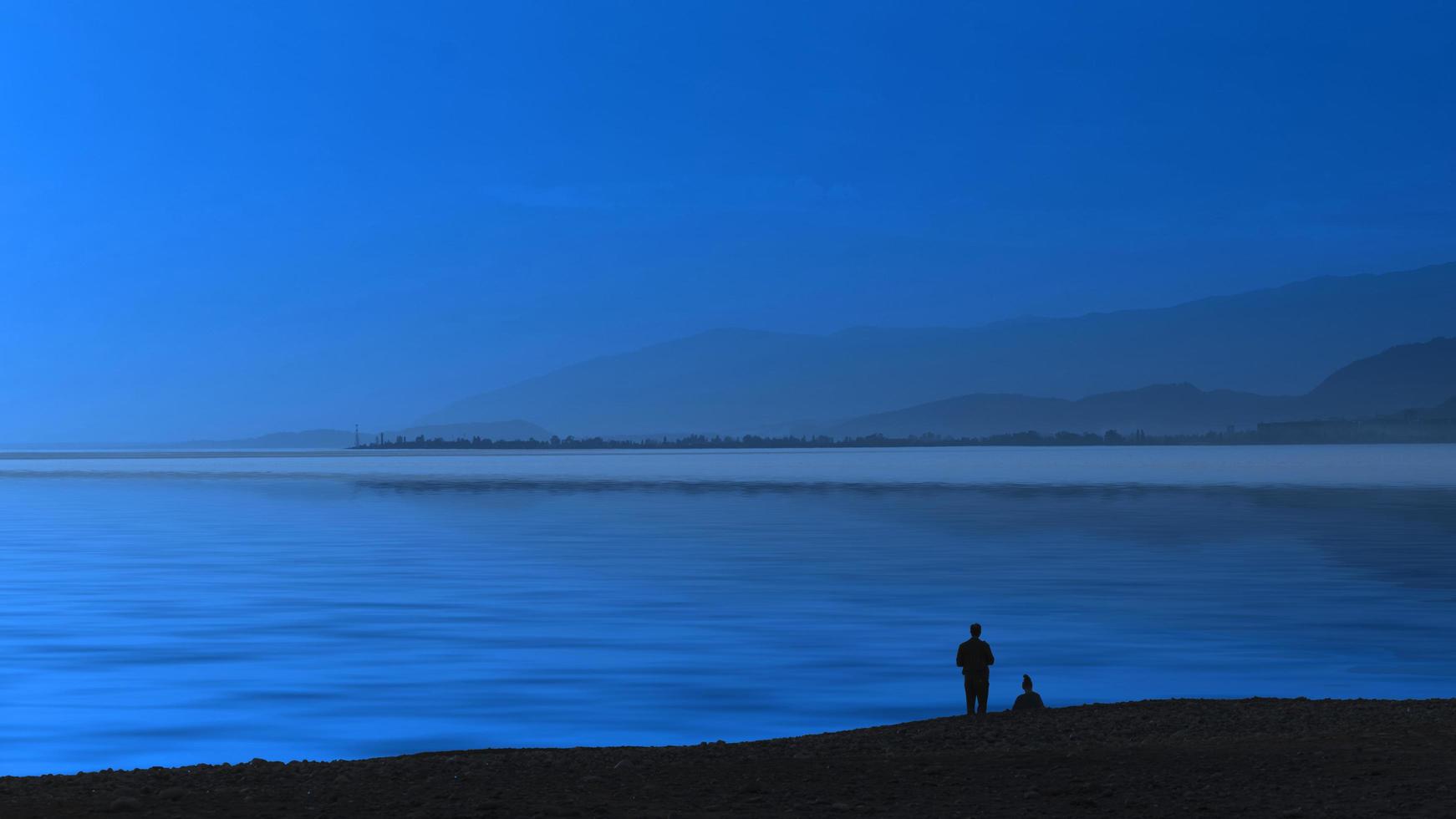 blauer Abend der Seelandschaft und Silhouetten von Menschen. foto