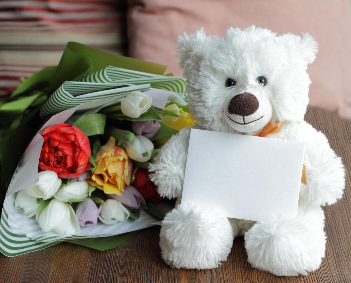 Teddybär und leere Postkarte mit Blumenstrauß foto
