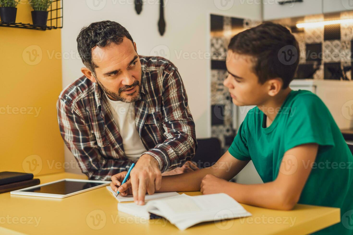 Vater ist Portion seine Sohn mit Lernen. Sie sind tun Hausaufgaben zusammen. foto