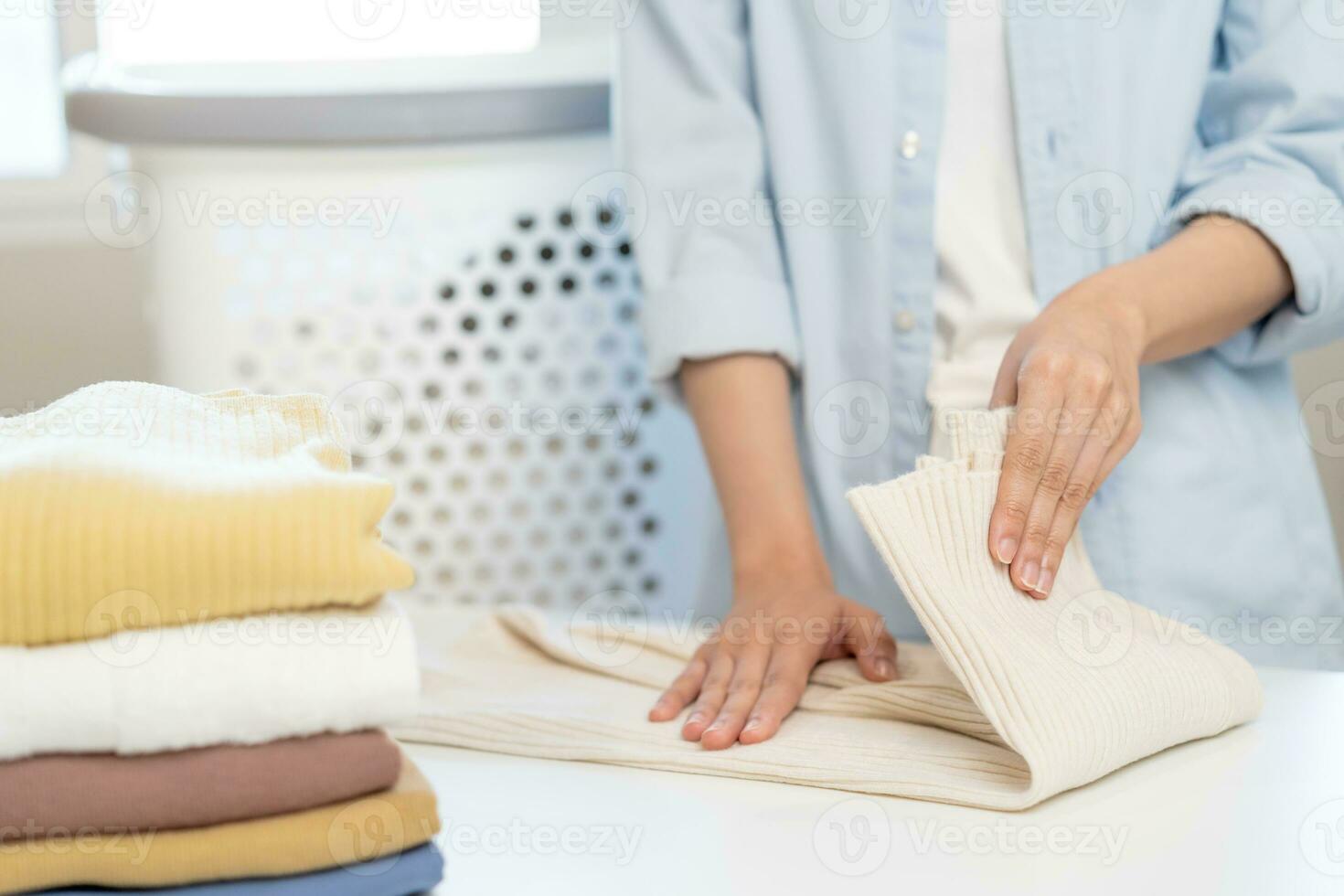 Hausfrau, asiatisch jung Frau Hand im viele falten frisch Hemden, Pullover oder Kleid auf Schreibtisch, Tabelle nach Waschen sauber Kleider und trocknen, Herstellung Haushalt Arbeiten im Zimmer beim heim. Wäsche und Dienstmädchen. foto