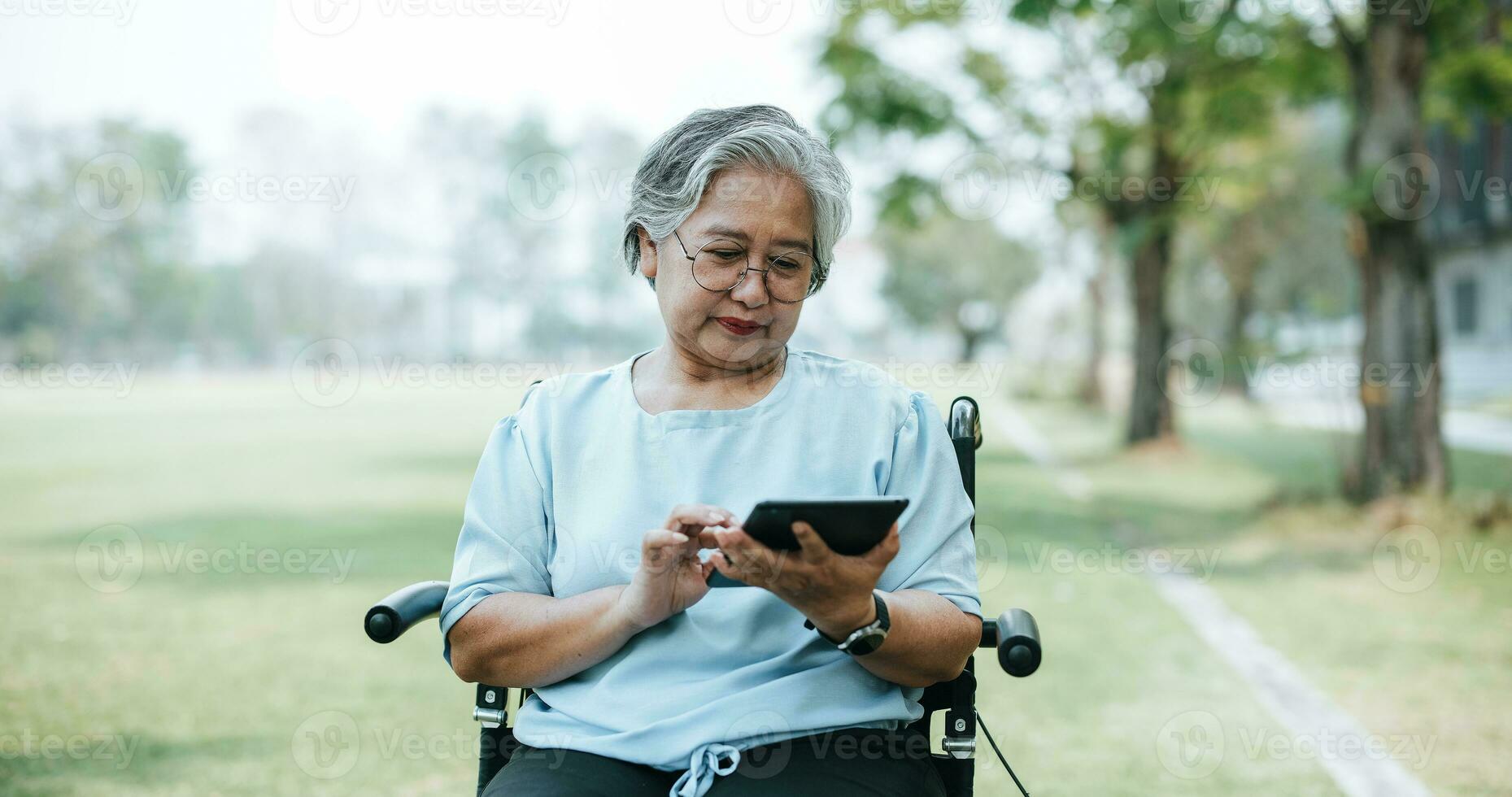 reifen asiatisch Frau auf Rollstuhl verwenden Tablette beim Gras Feld  23258974 Stock-Photo bei Vecteezy