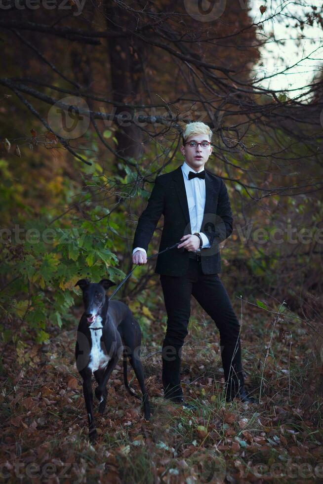 jung attraktiv Mann im passen und Krawatte mit ein Windhund Hund im Herbst draußen foto