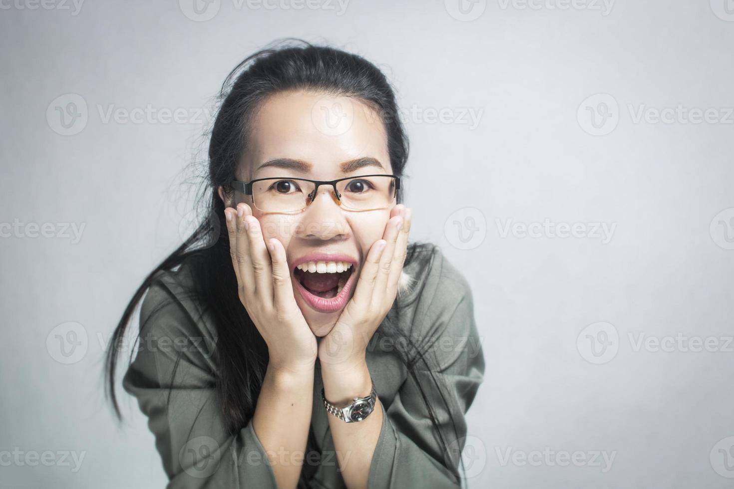 überraschte Frau, die Brille auf grauem Hintergrund trägt foto