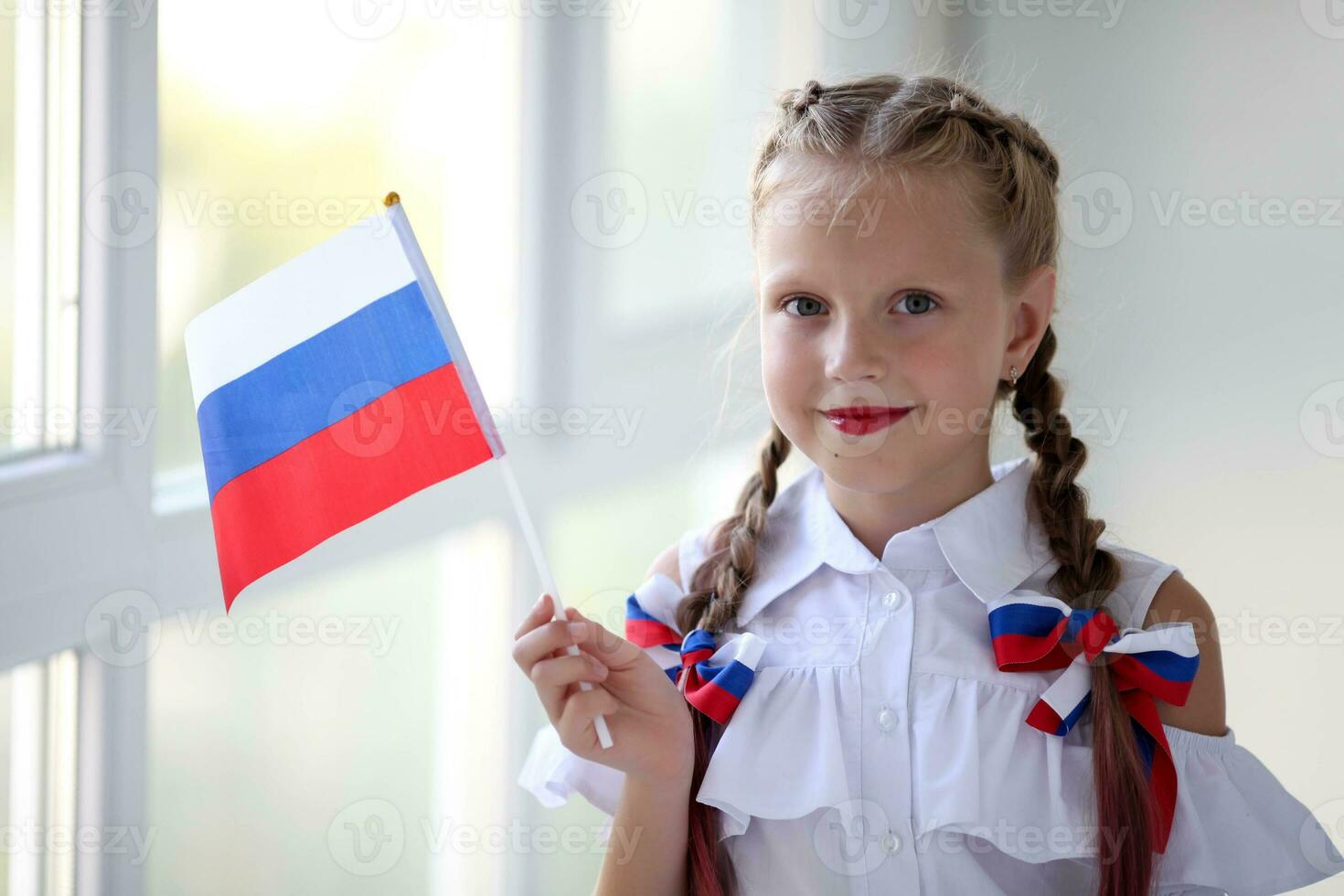 Schule Kind steht und hält das Flagge von Russland. wenig Mädchen mit Gesicht Gemälde von Russisch Symbolismus. Russisch Flagge Tag. foto