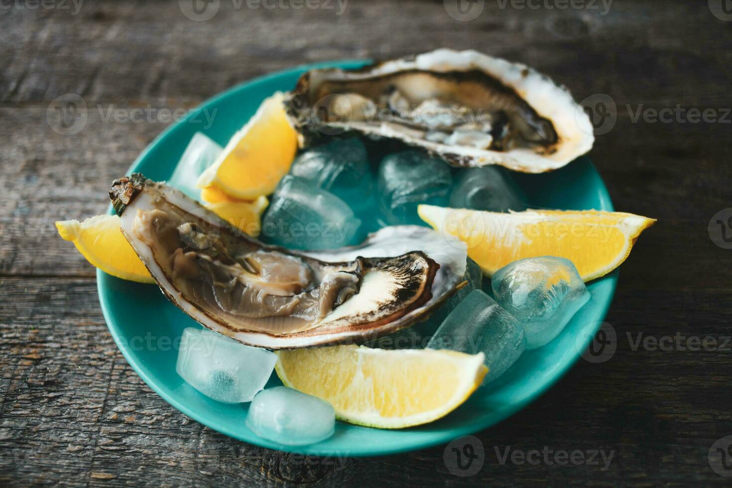 Nahansicht von frisch öffnen roh Austern auf ein Blau Platte, mit Zitrone und Eis. gesund Meeresfrüchte. Aussicht von über. Kopieren Raum. Meeresfrüchte. Gourmet Lebensmittel. foto