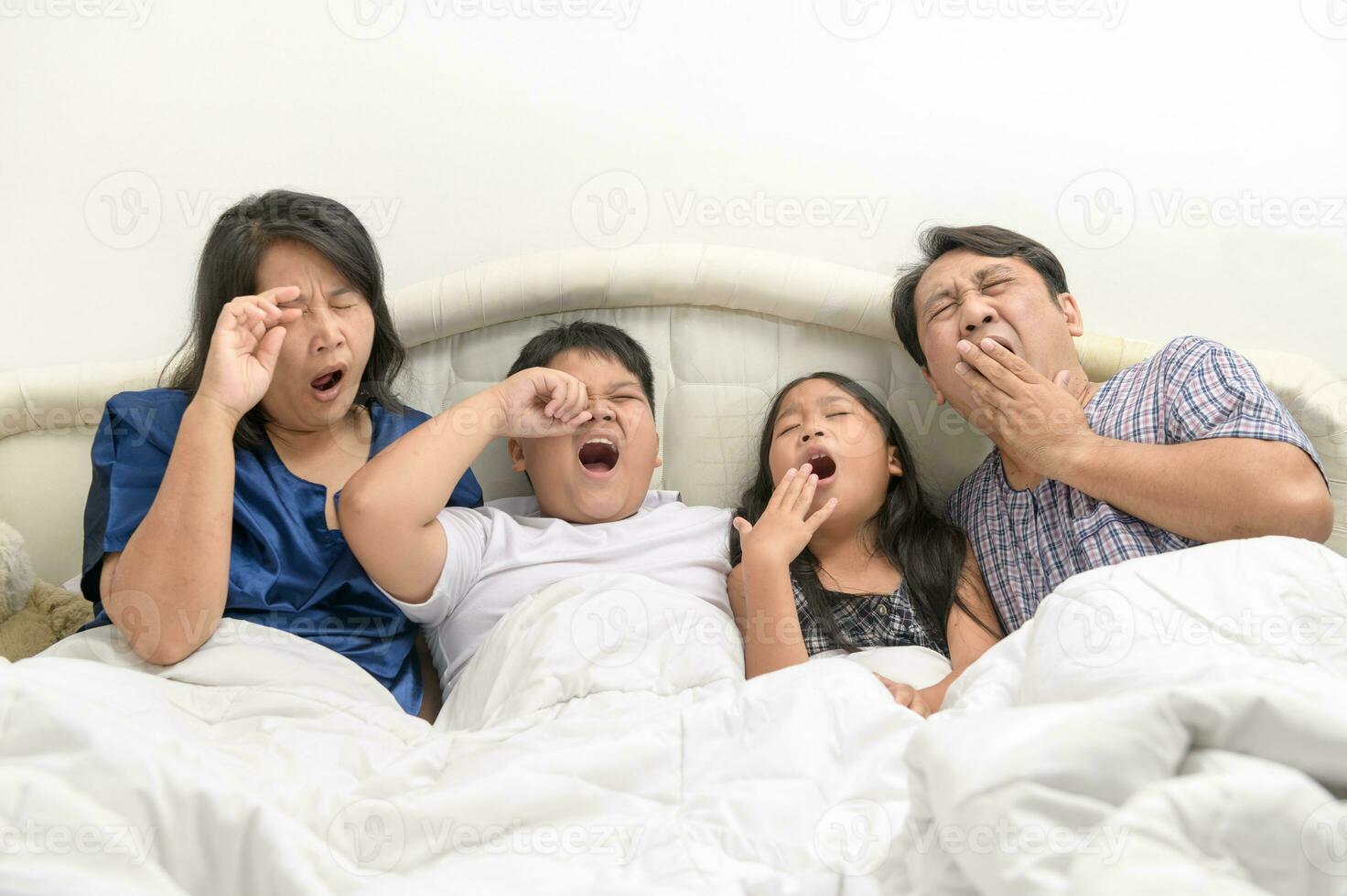 Vater und Mutter mit Kinder Gähnen und Dehnen im Bett, foto