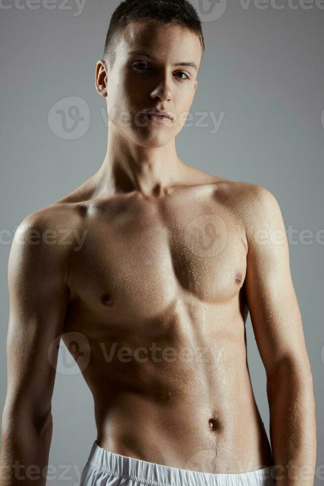 Porträt von ein jung Athlet mit ein aufgepumpt Torso auf ein grau Hintergrund abgeschnitten Aussicht foto