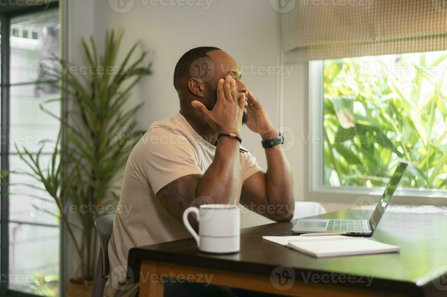 stressig afrikanisch amerikanisch Mann Arbeiten im seine Zuhause foto