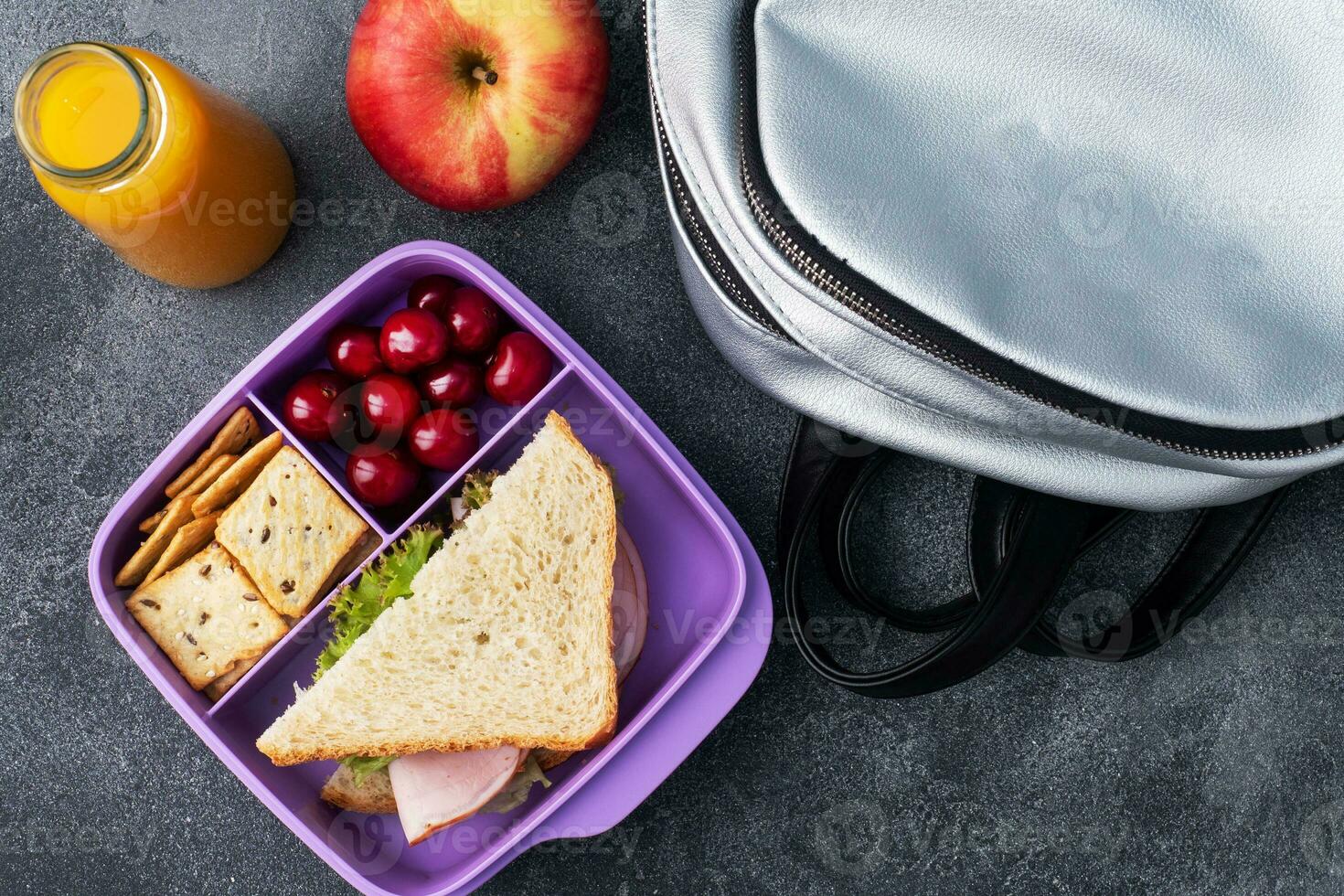 leckeres gesundes Sandwich in einer Brotdose, Keksen und Kirschen. Mittagessen mit in die Schule oder ins Büro nehmen. Saft in einer Flasche und einem Apfel. foto