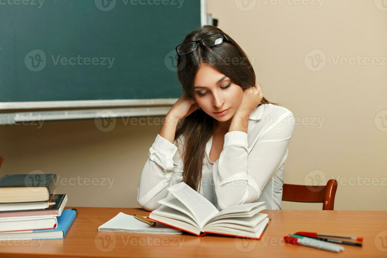 schön jung Frau mit Brille lesen ein Buch im das Klassenzimmer. foto