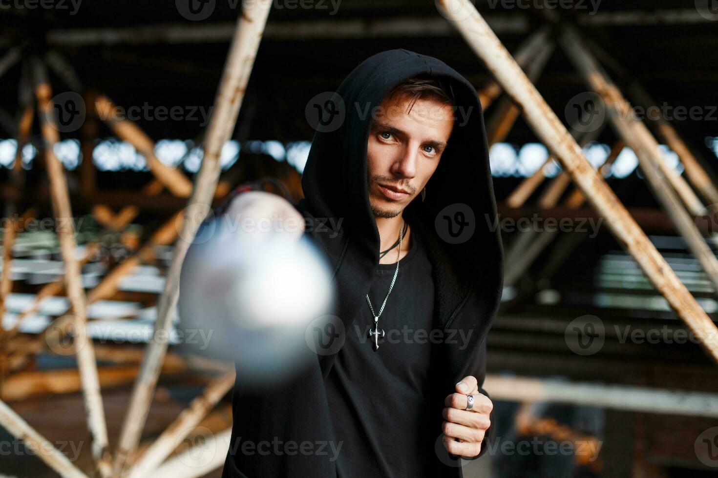 aggressiv Mann schlägt das Schläger. stilvoll Kerl im schwarz Kleider mit ein Haube. foto