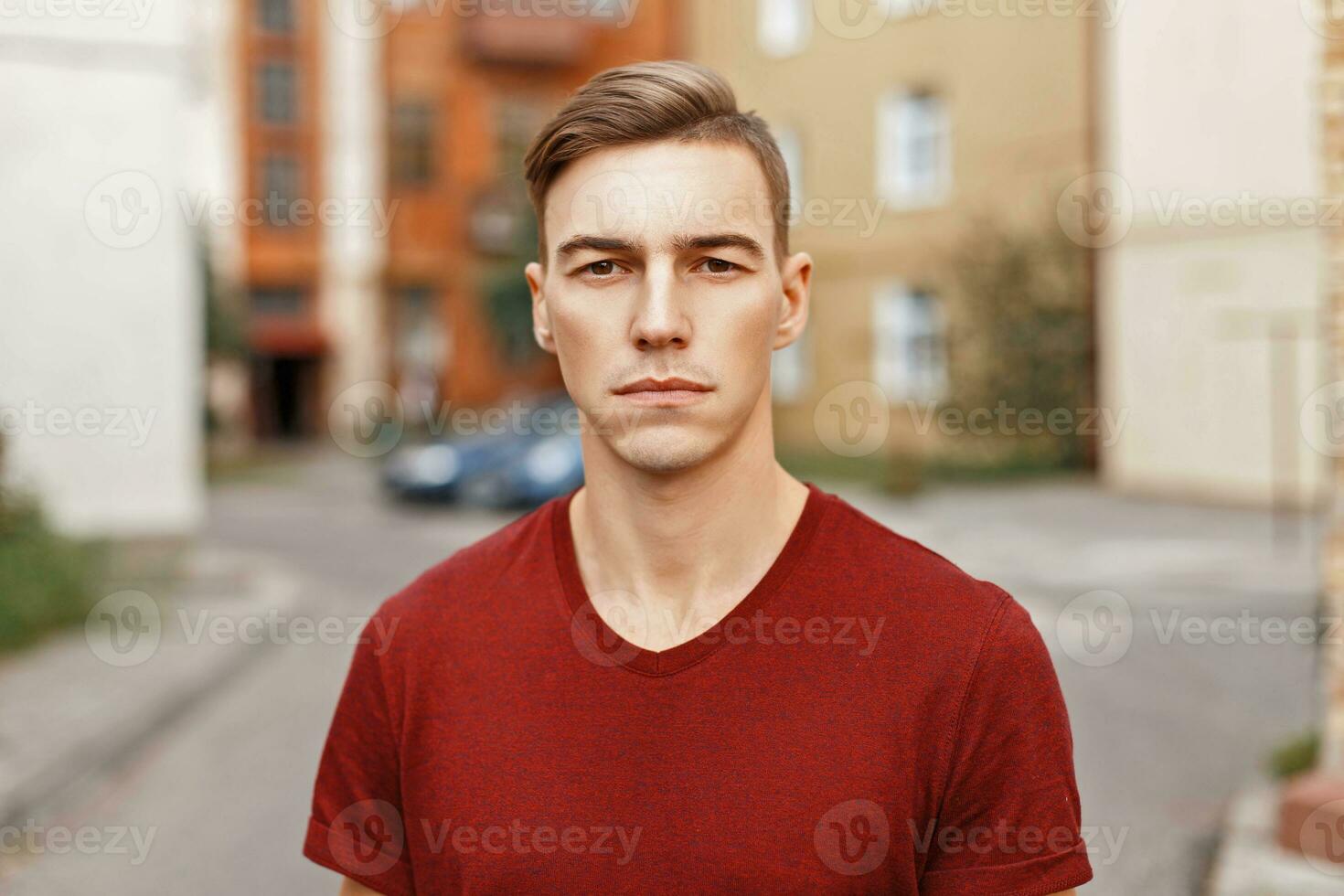 gut aussehend jung Mann mit Haar im ein rot Hemd steht im ein alt Hof foto