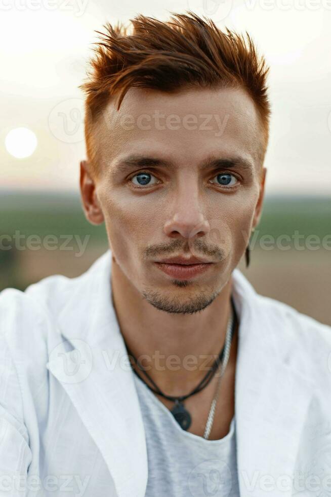 Porträt von ein jung gut aussehend Kerl im ein Weiß passen beim Sonnenuntergang foto