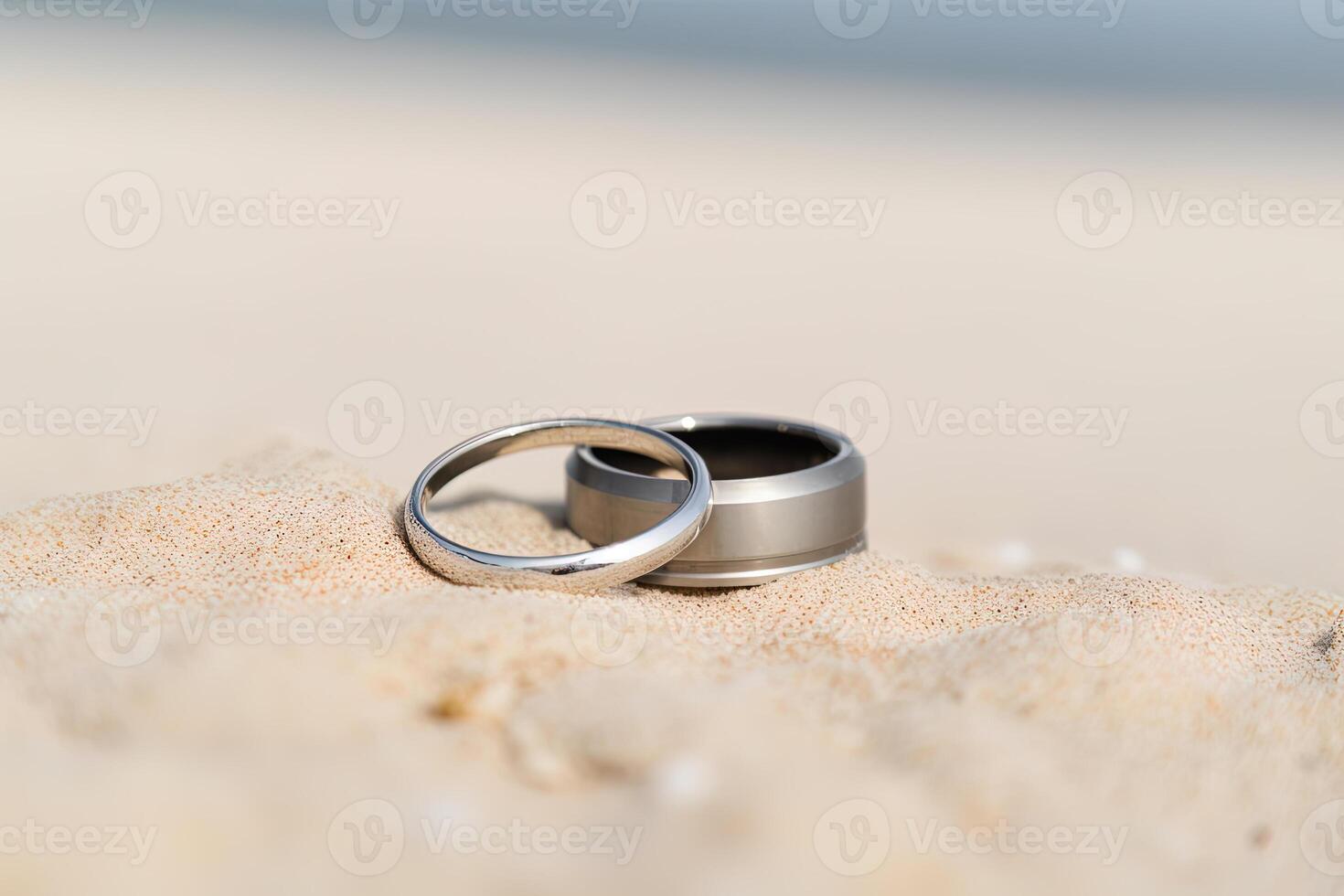 zwei Hochzeit Ringe im das Sand auf das Hintergrund von ein Strand und Meer. ai generiert foto