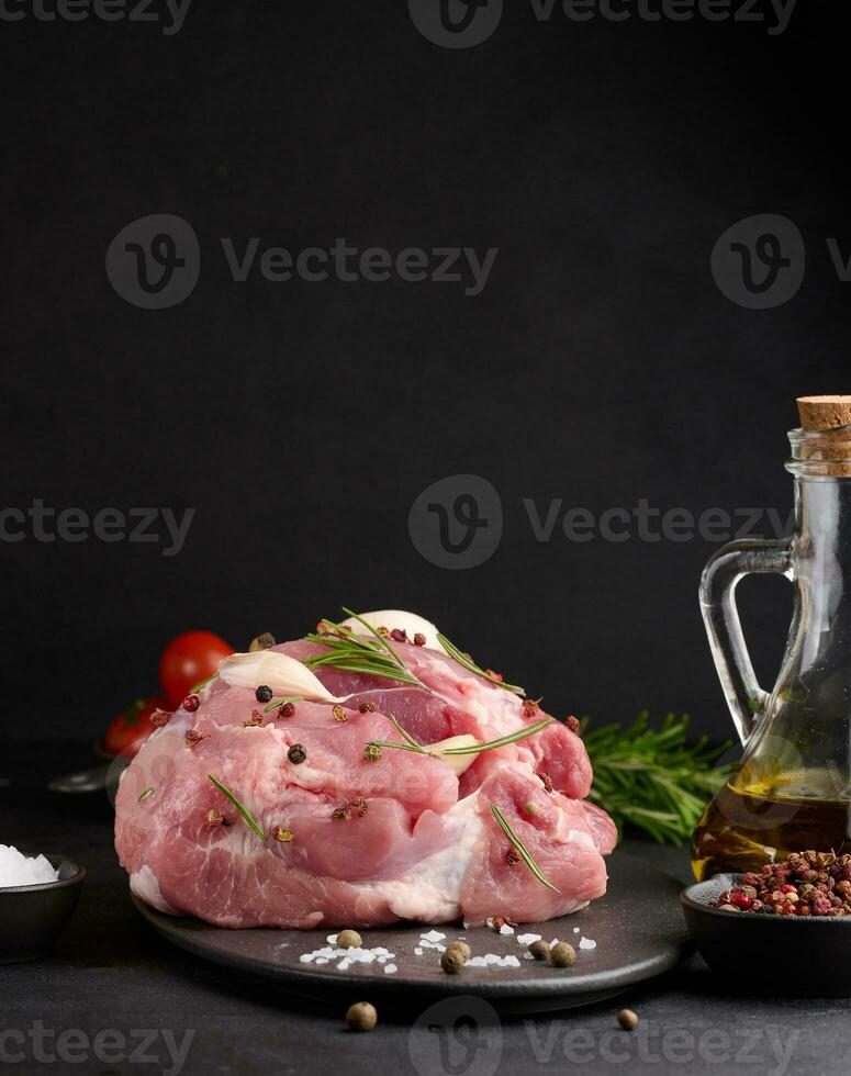 ein Stück von Schweinefleisch Schinken auf ein schwarz Tafel und Gewürze Olive Öl, Salz, Rosmarin Ast und Pfeffer foto