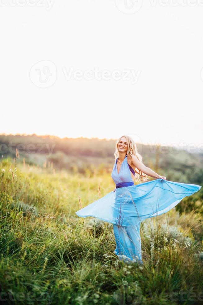 blondes Mädchen mit losen Haaren in einem hellblauen Kleid und einem Mann im Licht des Sonnenuntergangs foto