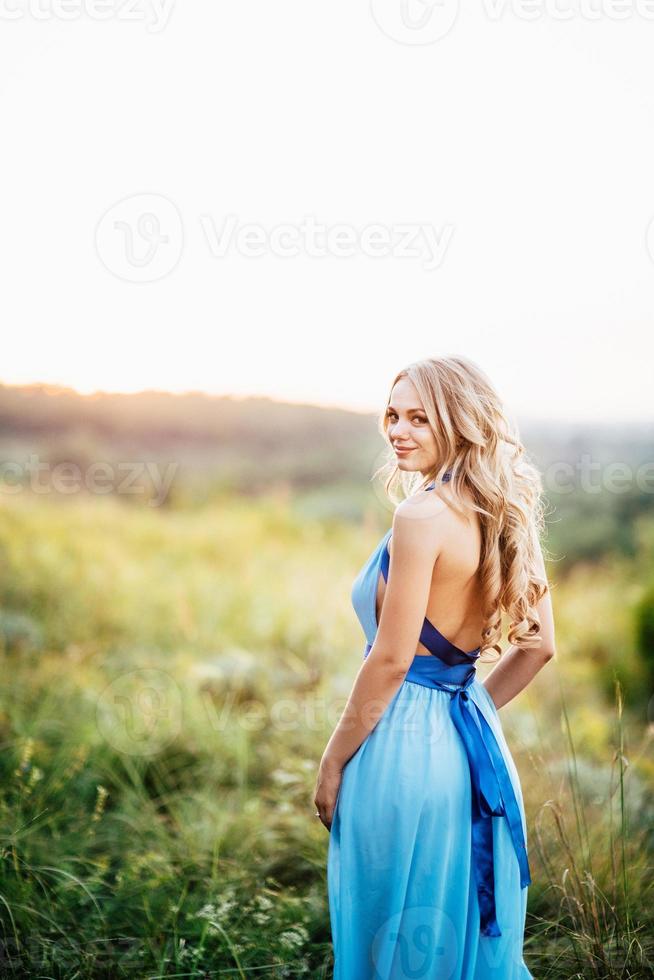 blondes Mädchen mit losen Haaren in einem hellblauen Kleid und einem Mann im Licht des Sonnenuntergangs foto