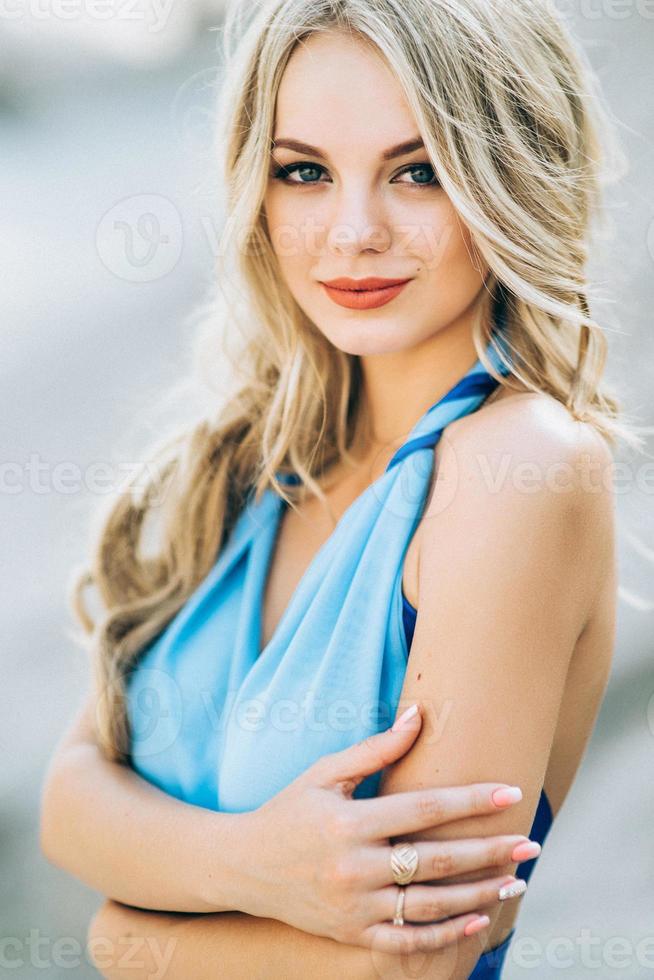 blondes Mädchen in einem hellblauen Kleid in einem Granitsteinbruch foto