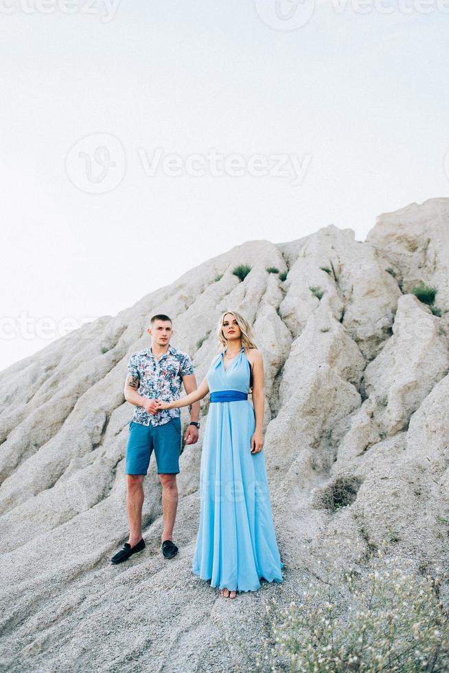 blondes Mädchen in einem hellblauen Kleid und ein Mann in einem hellen Hemd in einem Granitsteinbruch foto