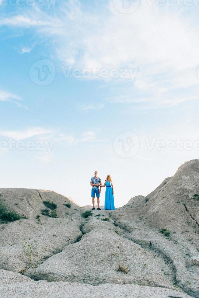 blondes Mädchen in einem hellblauen Kleid und ein Mann in einem hellen Hemd in einem Granitsteinbruch foto