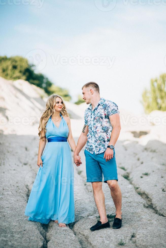 blondes Mädchen in einem hellblauen Kleid und ein Mann in einem hellen Hemd in einem Granitsteinbruch foto