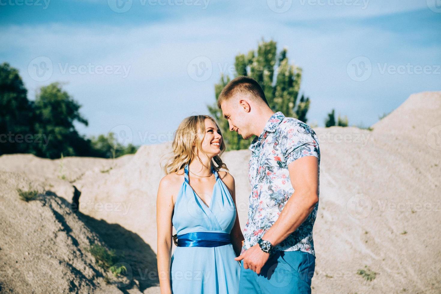 blondes Mädchen in einem hellblauen Kleid und ein Mann in einem hellen Hemd in einem Granitsteinbruch foto