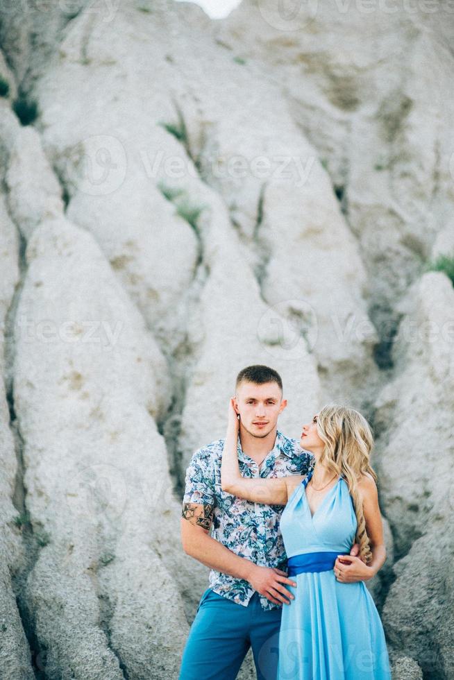 blondes Mädchen in einem hellblauen Kleid und ein Mann in einem hellen Hemd in einem Granitsteinbruch foto