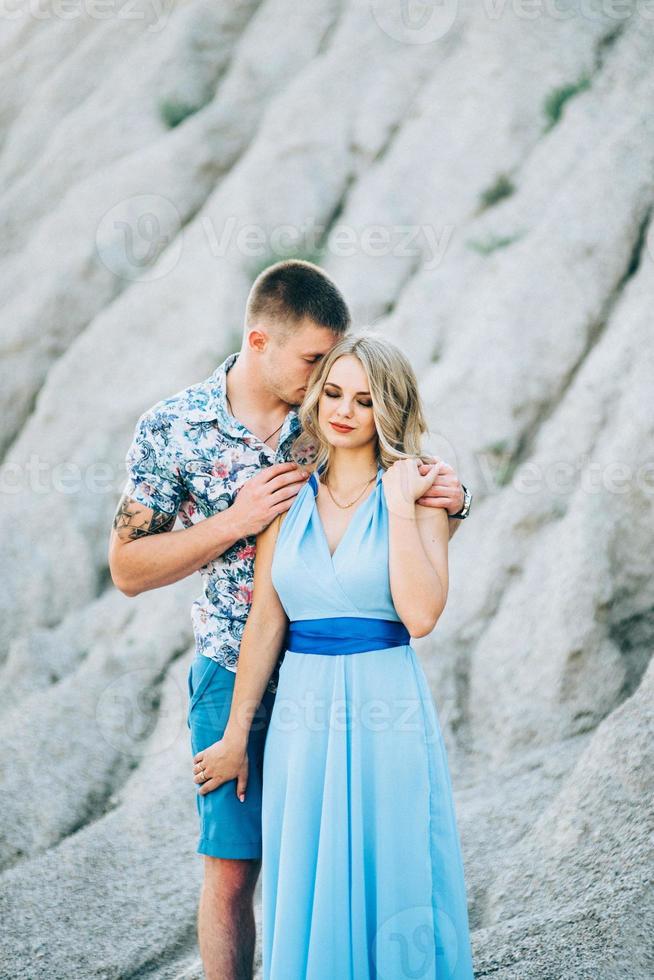 blondes Mädchen in einem hellblauen Kleid und ein Mann in einem hellen Hemd in einem Granitsteinbruch foto