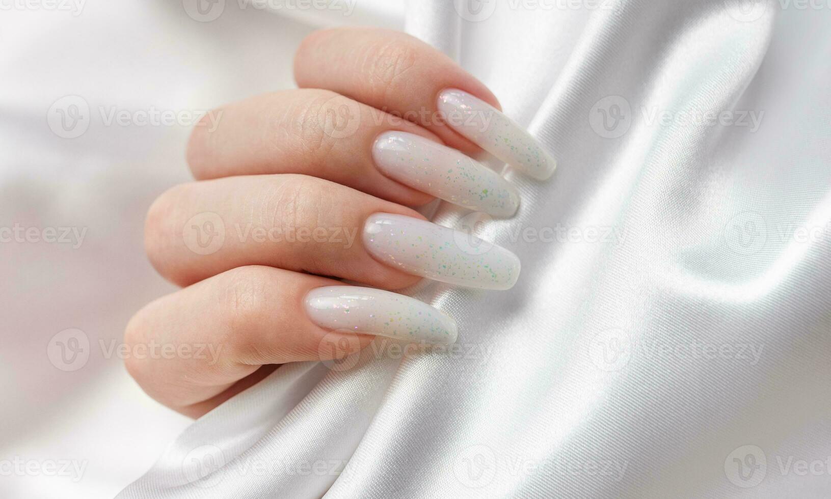 ein Frau Hände mit ein Maniküre auf ihnen, das Nägel sind gemalt im ein Weiß Farbe. foto