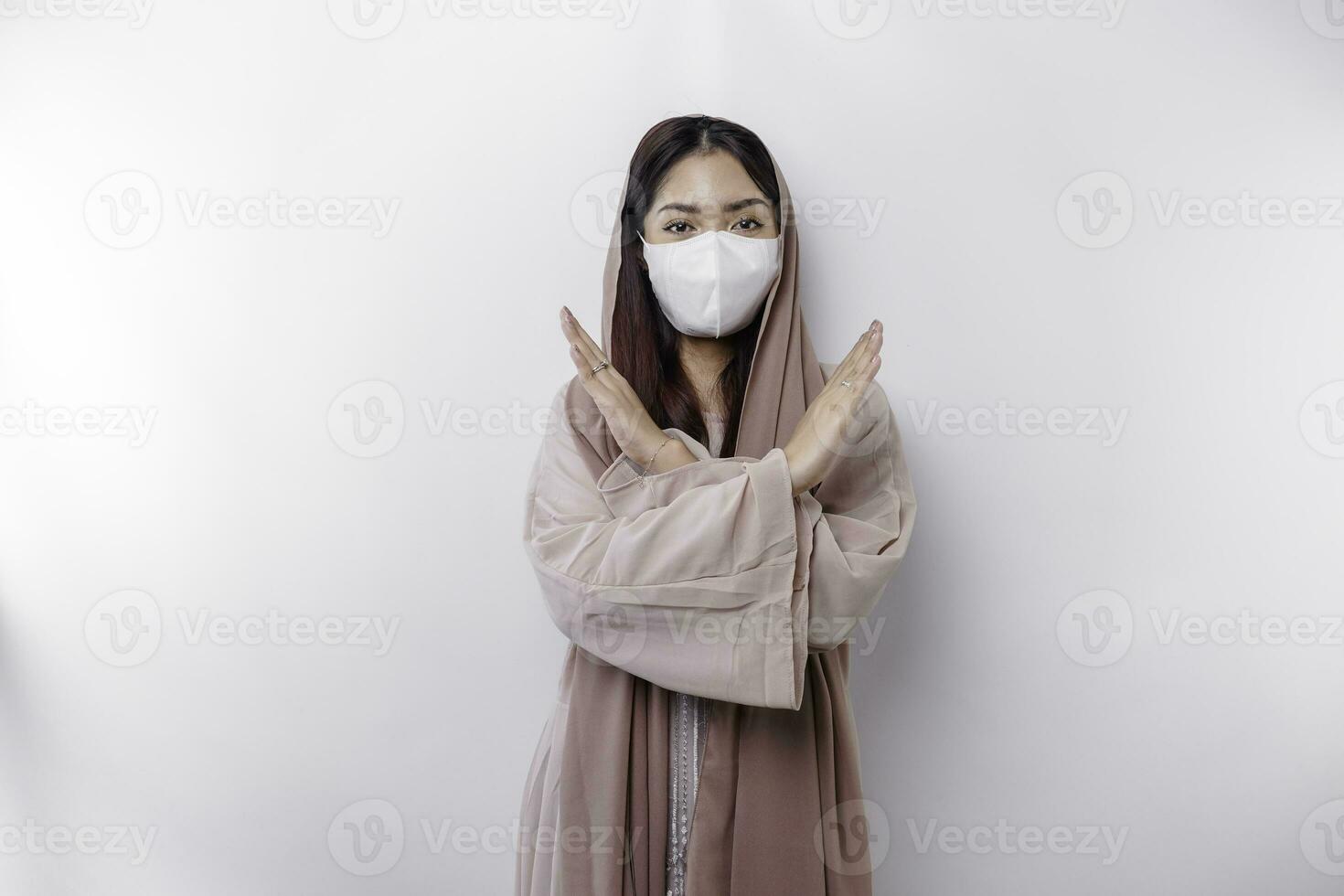 ein vorsichtig asiatisch Muslim Frau tragen ein Maske wie ein vorbeugend zum covid-19 mit Hand Geste Pose Ablehnung oder Verbot foto