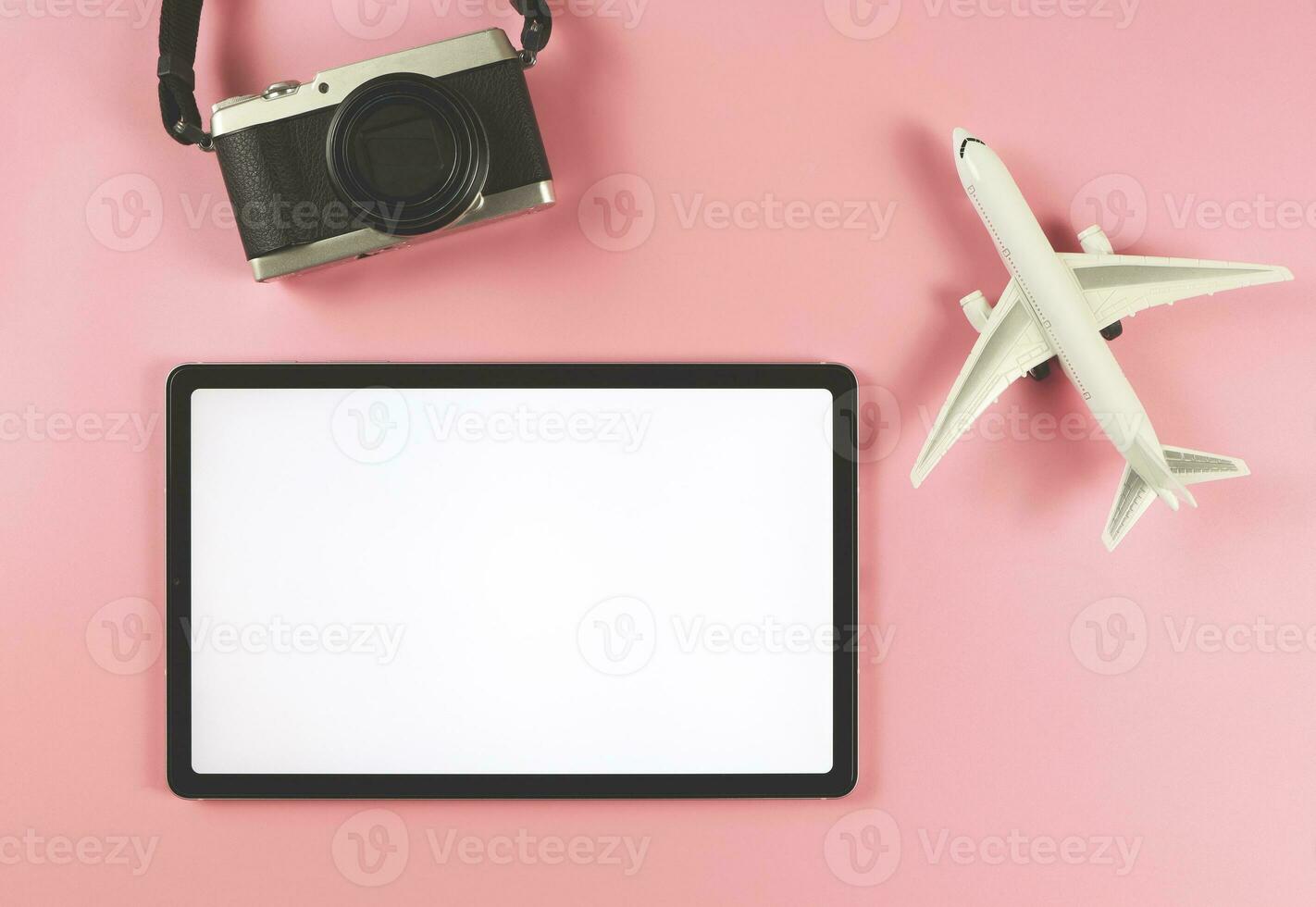eben legen von Digital Tablette mit leer Weiß Bildschirm, Flugzeug Modell- und Digital Kamera isoliert auf Rosa Hintergrund. Reise Planung Konzept. foto