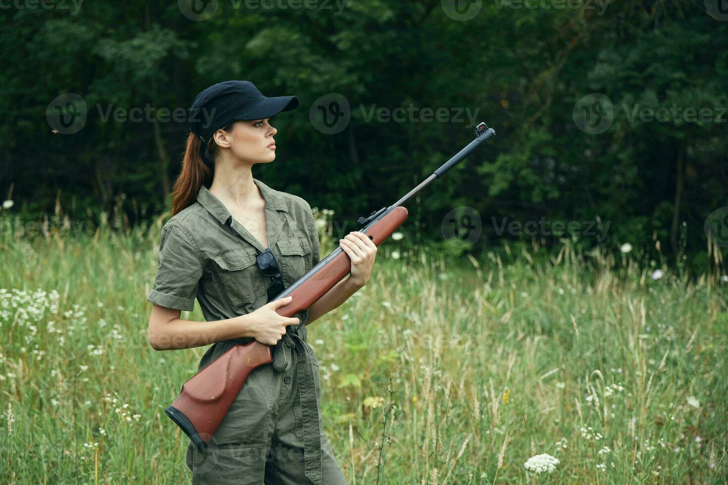 Frau Soldat mit ein Gewehr im seine Hände Grün Overall schwarz Baseball Deckel foto