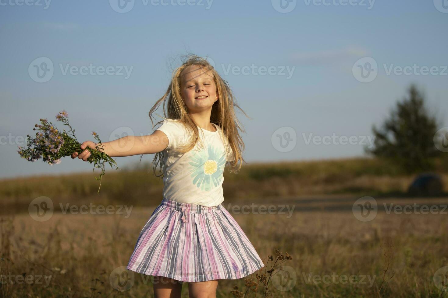 schön wenig Mädchen mit ein Strauß von wild Blumen auf ein Hintergrund von das Himmel. ein glücklich Kind auf ein Sommer- Wiese. foto