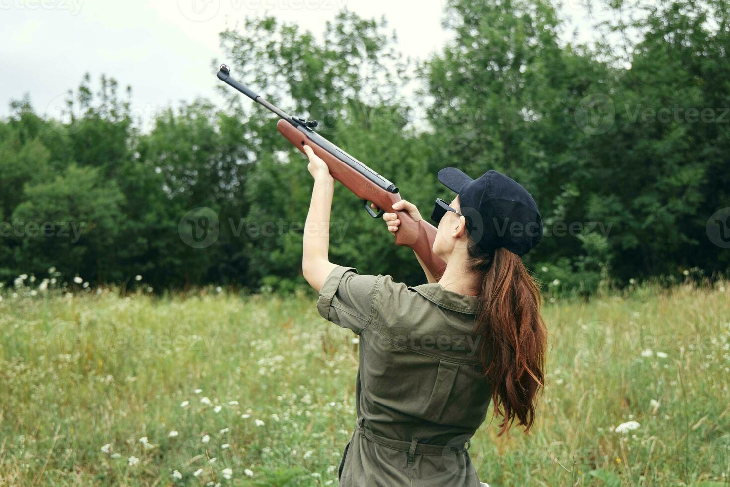 Militär- Frau halten Gewehr oben Sicht Jagd zurück Aussicht frisch Luft Grün foto