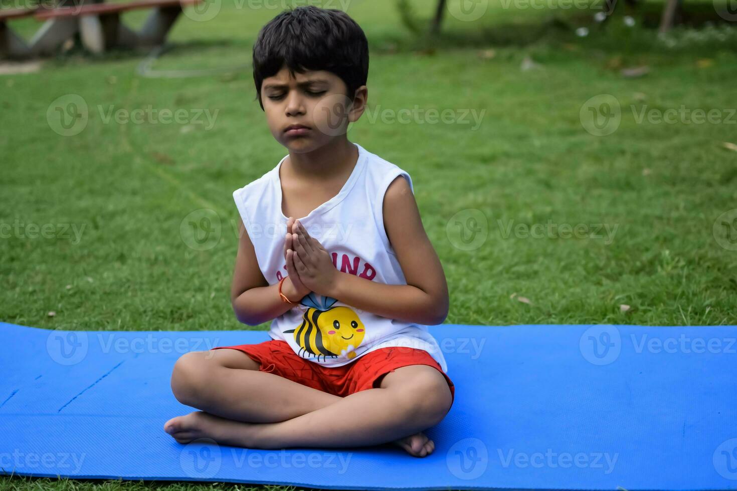 asiatisch Clever Kind tun Yoga Pose im das Gesellschaft Park draussen, Kinder- Yoga Pose. das wenig Junge tun Yoga und Meditation Übung. foto