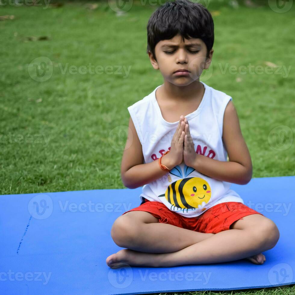 asiatisch Clever Kind tun Yoga Pose im das Gesellschaft Park draussen, Kinder- Yoga Pose. das wenig Junge tun Yoga und Meditation Übung. foto