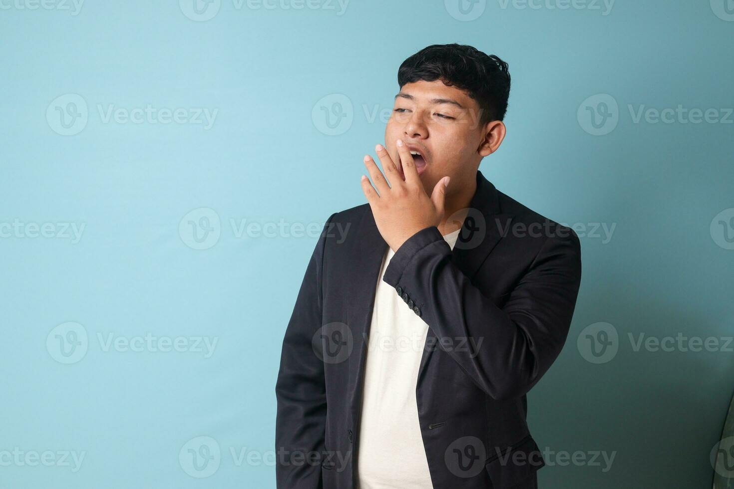 Porträt von jung asiatisch Geschäft Mann im beiläufig passen Gähnen im gelangweilt Ausdrücke. isoliert Bild auf Blau Hintergrund foto
