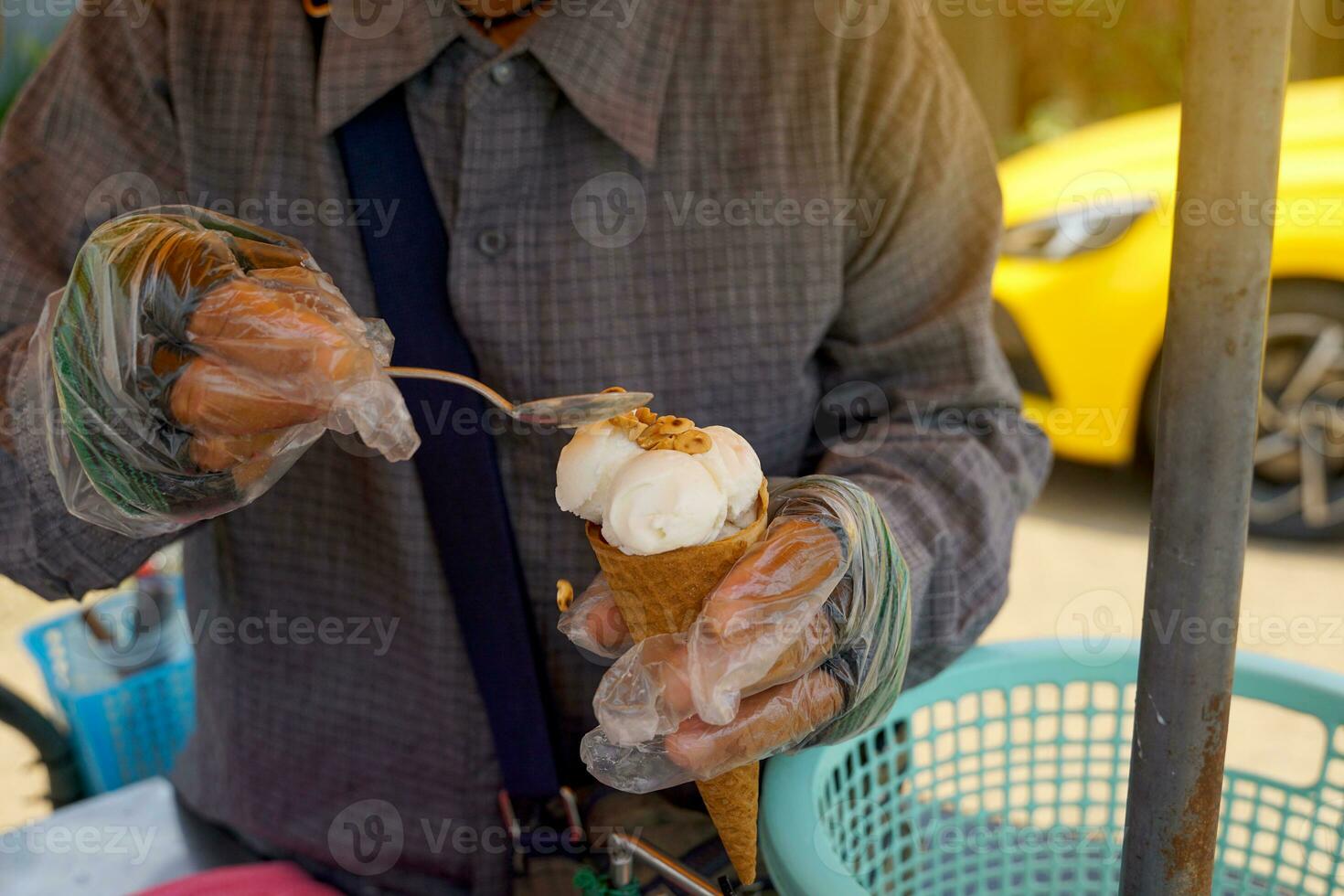 Straße Verkäufer Verkauf hausgemacht Eis Sahne Prise geröstet Erdnüsse auf Eis Sahne Zapfen Kokosnuss Milch Geschmack zum Kunden zu Befehl. Sanft und selektiv Fokus. foto