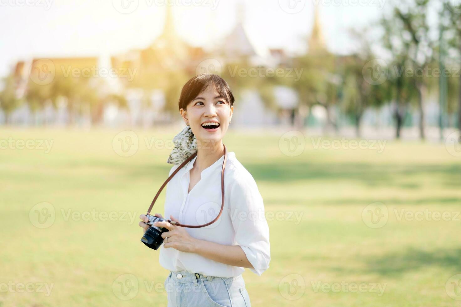 Porträt von asiatisch Frau Reisender mit Kamera. Asien Sommer- Tourismus Ferien Konzept mit das großartig Palast im ein Hintergrund beim Bangkok, Thailand foto