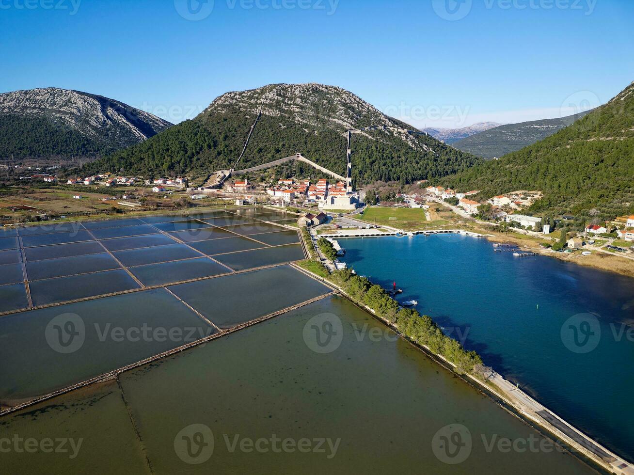 luftdrohnenansicht der salzpfanne in der stadt ston in kroatien. Festungsmauern in den Hügeln im Hintergrund. Salzfelder. Salzwerke Stein. tourismus in der nähe der adria. historische Besuche. foto