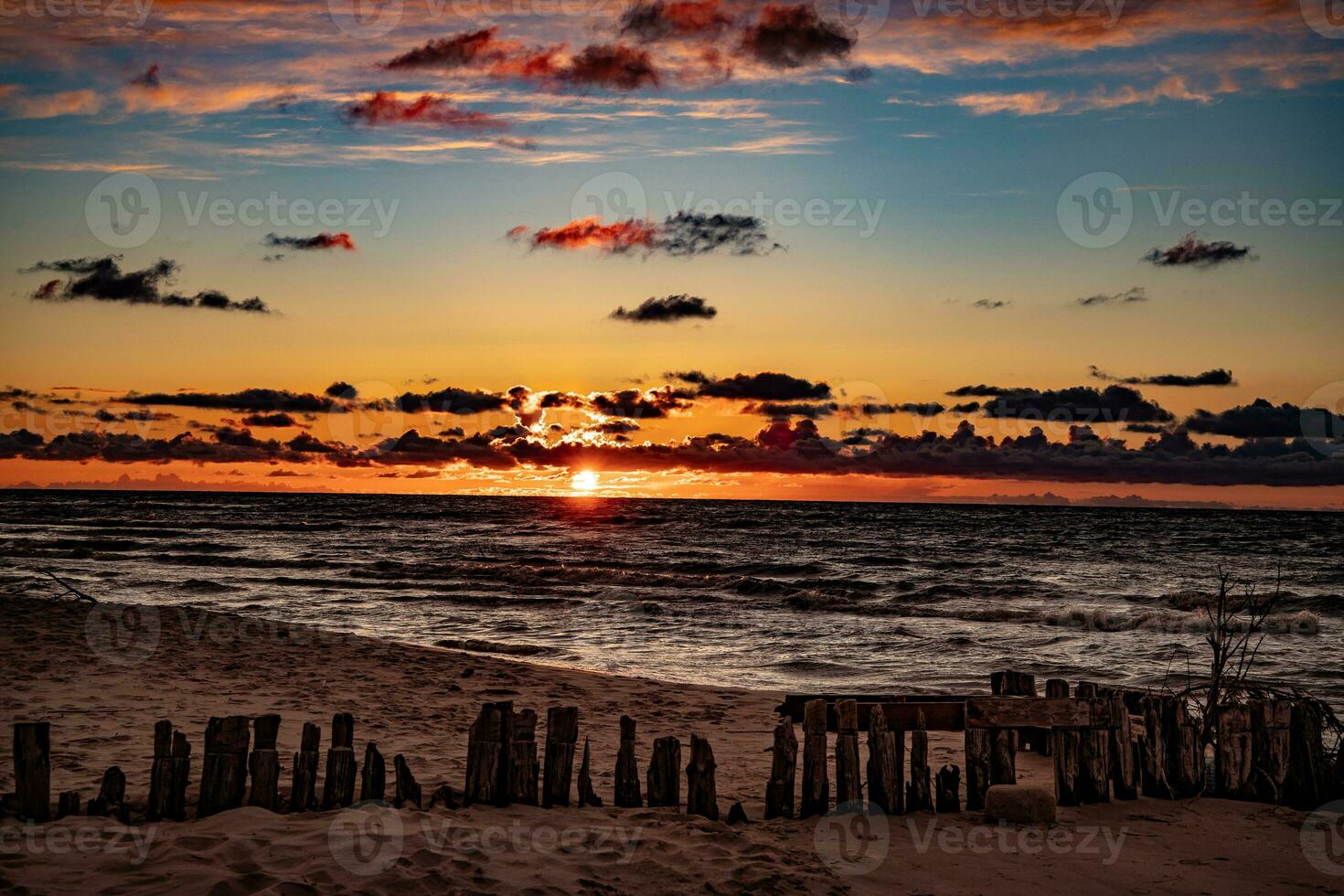 bunt Sonnenuntergang Über das Polieren baltisch Meer mit dunkel Himmel Wolken und Wellenbrecher foto