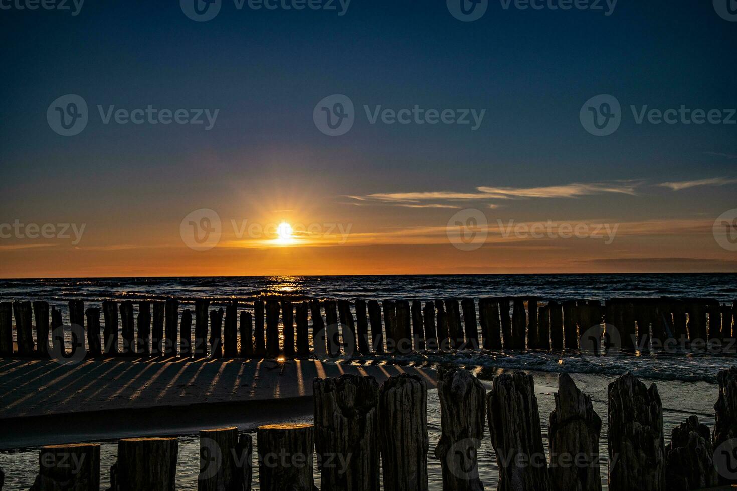 bunt Sonnenuntergang Über das Polieren baltisch Meer mit dunkel Himmel Wolken und Wellenbrecher foto