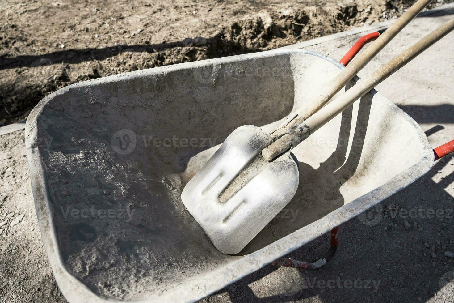 Alte, zuverlässig funktionierende Schubkarre mit Schaufeln auf einer Baustelle foto